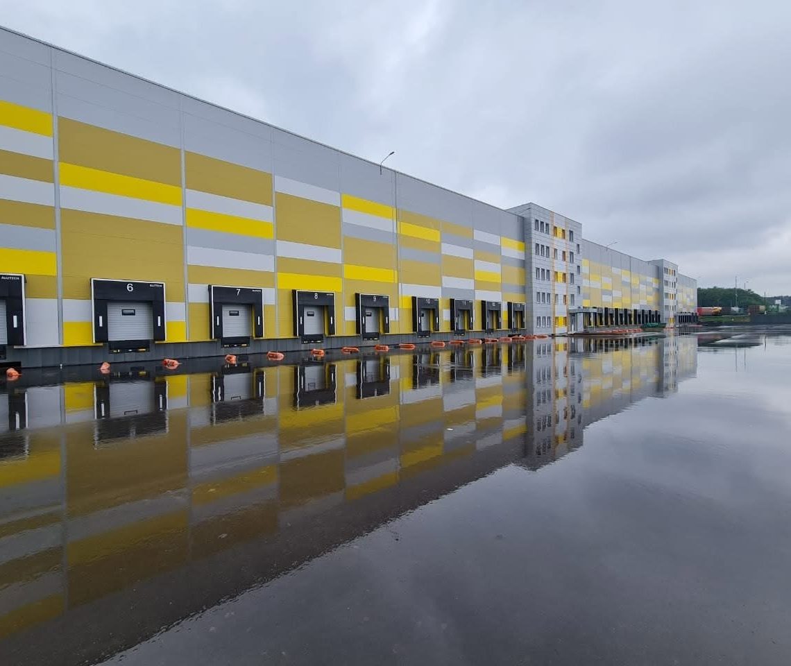 Фасад склада BIOCARD в Вырубово: жёлто-серые панели и ряд погрузочных ворот с номерами